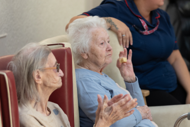 Residents joining in a seated activity with staff support